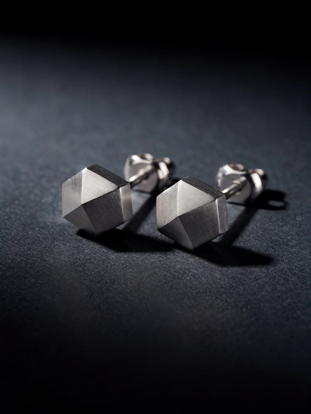 Minimalist geometric sterling silver earrings on stone pedestal