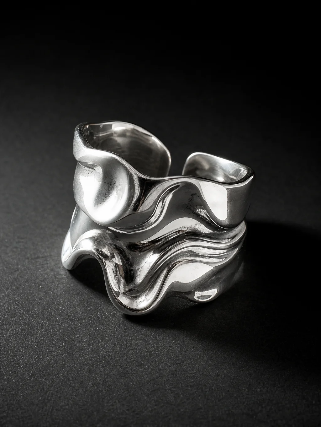 Sculptural molten silver bangle and ring on dark raw slate